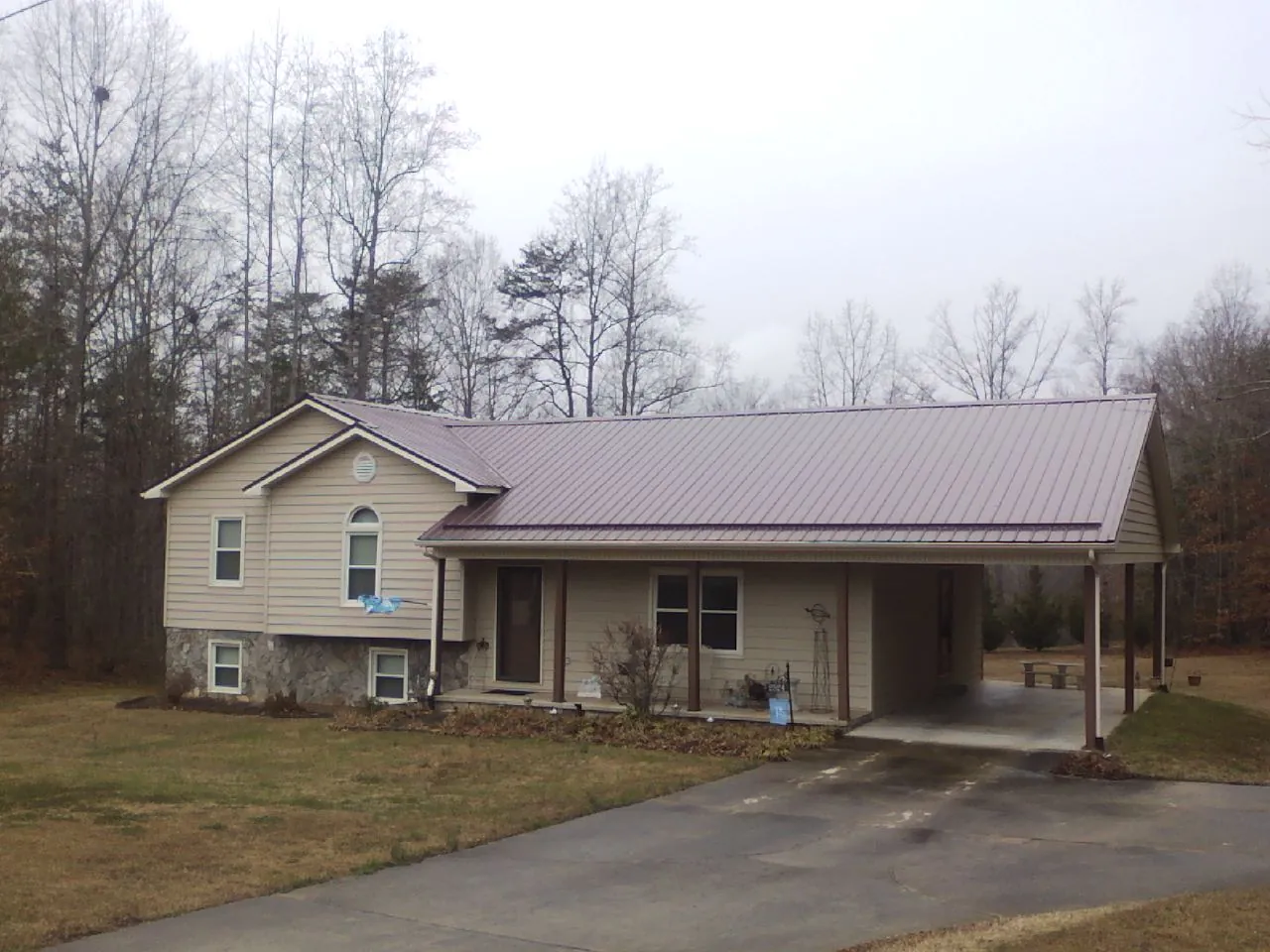 Burgundy metal roof on a tan split level home with an attached carport in Eldridge