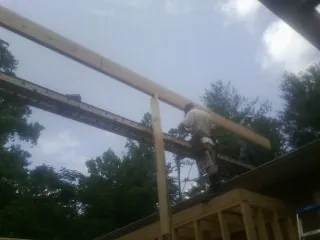 Carpenter setting a ridge beam over a new addition frame — Ice Dam Removal by Roofing Brothers in Eldridge