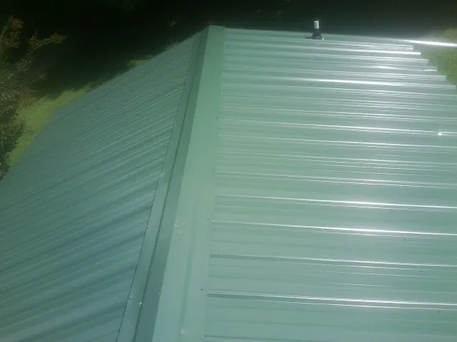 New green metal panels meeting at the ridge of a roof — Flat Roof Repair work by our crew in Eldridge