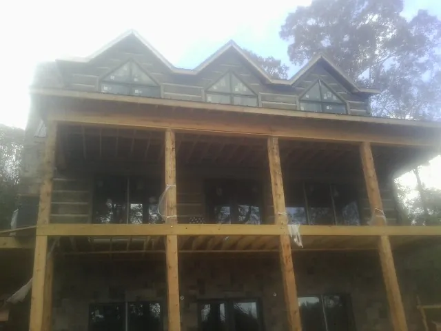 Dormers and porch framing on a large log home under construction — Roof Coating work by our crew in Eldridge