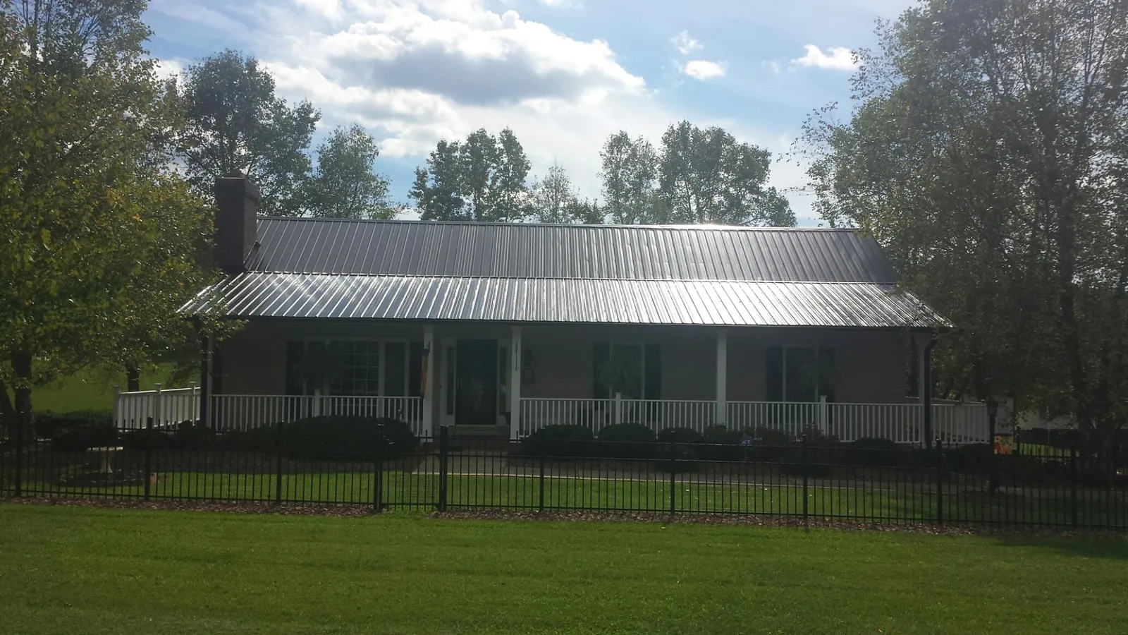 Gray metal roof on a brick ranch with a full width front porch — Gutter Guard Installation work by our crew in Eldridge