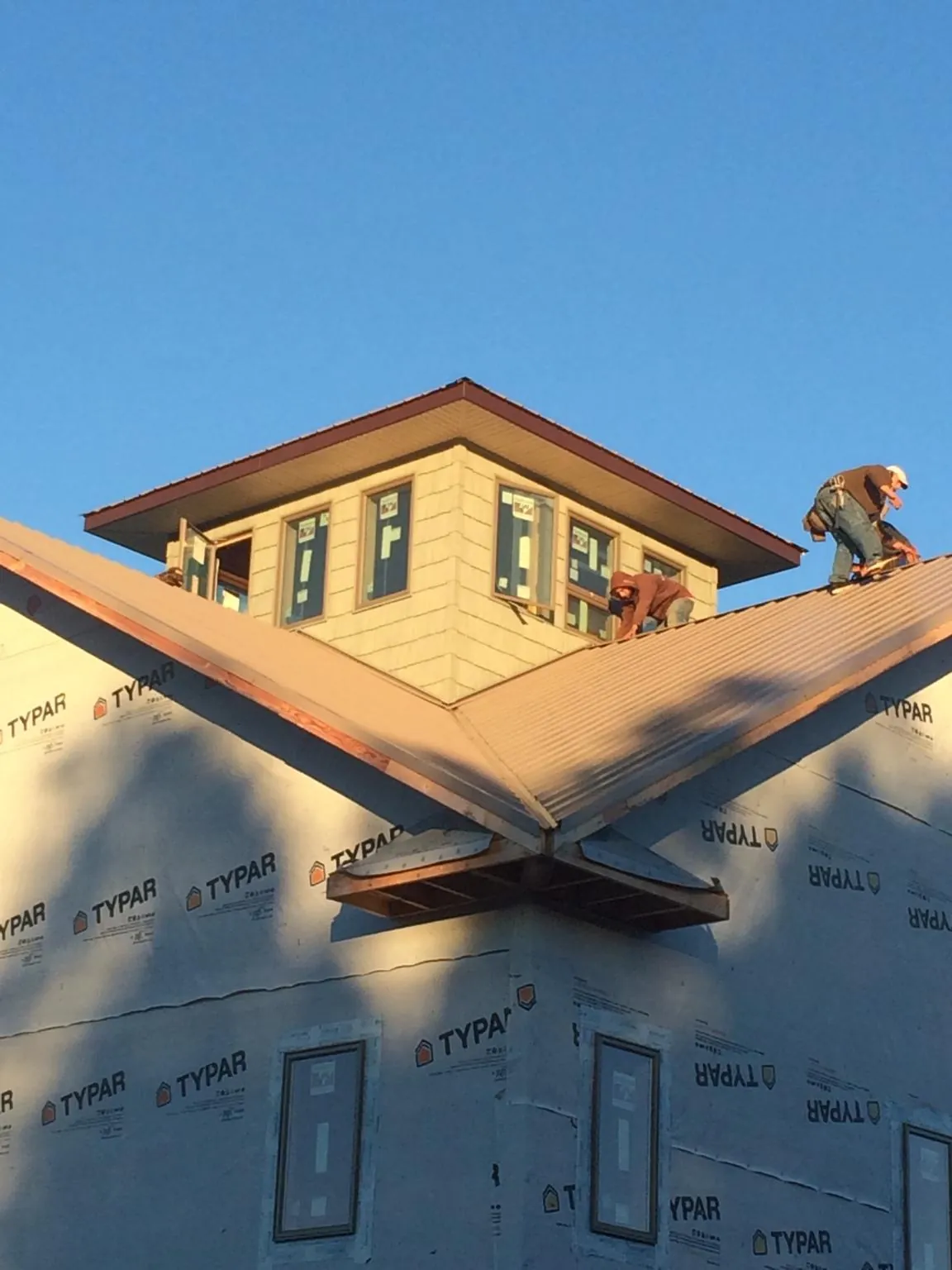 Roofers working around a rooftop cupola on a new metal roof at sunset — Roof Waterproofing in Eldridge by Roofing Brothers